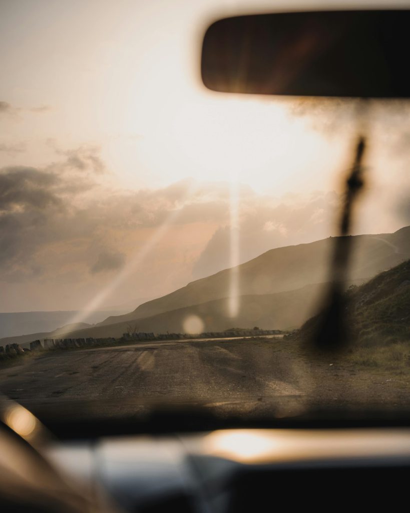 Captivating view of a road through hills at sunset, framed from a car interior.